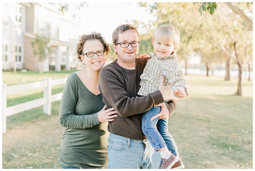 Family Photos at Morrison Ranch standing next to big trees, white picket fence, and green grass