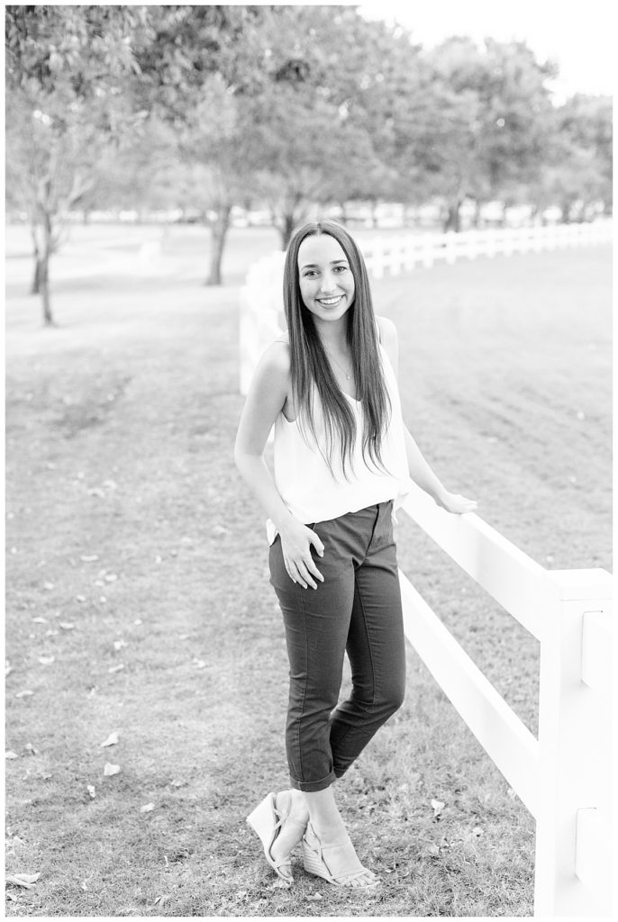 a girl standing in a field next to a white picket fence in Morrison Ranch