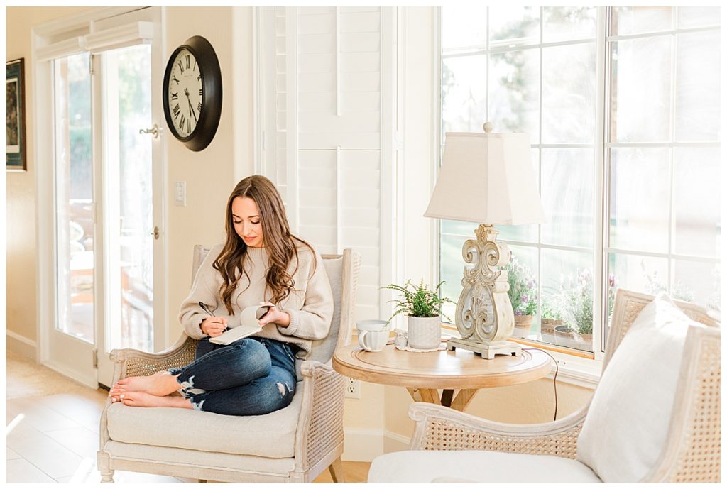 Girl journalling in a nook with two chairs about the difference of living in burnout vs. God's rest