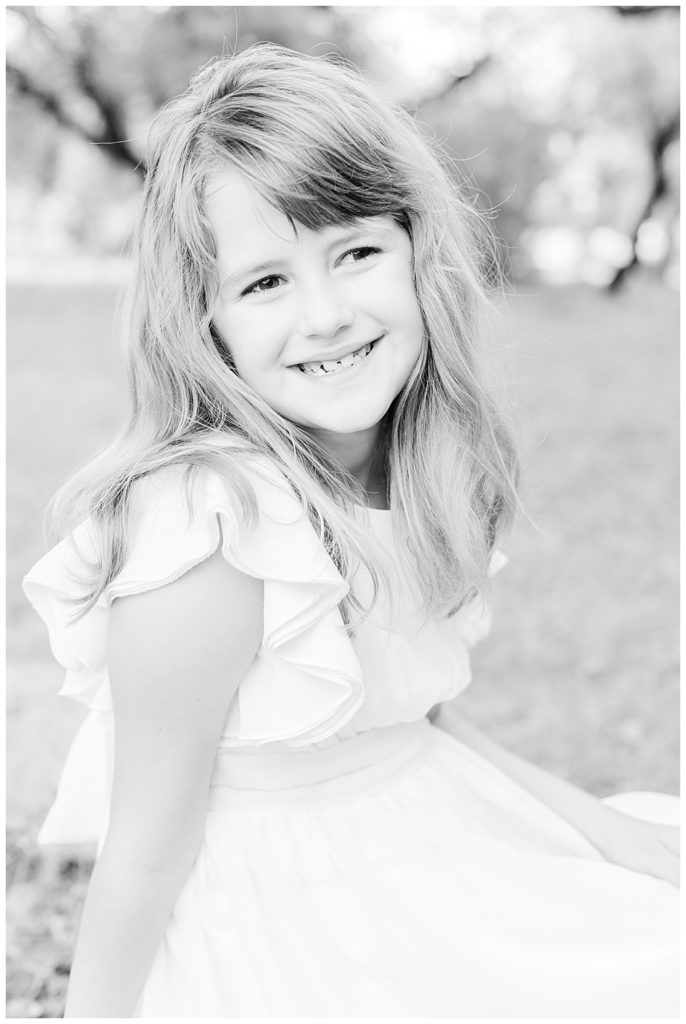 black and white photo of a little girl in a white dress smiling 