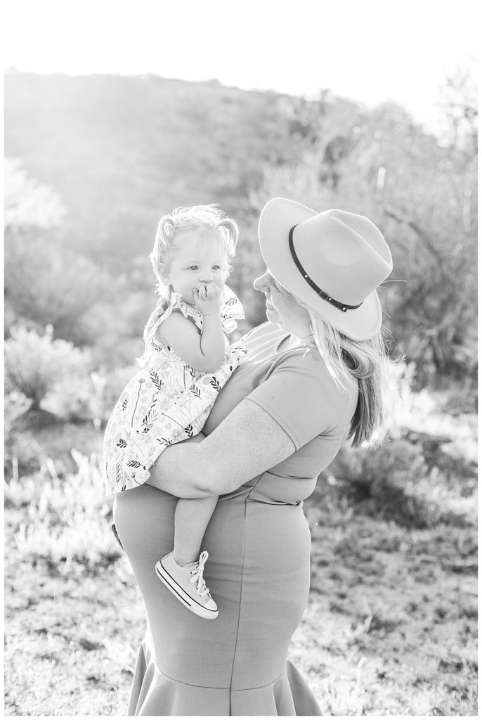 black and white photo of little girl sitting on mom's baby bump, Arizona Desert Maternity Session