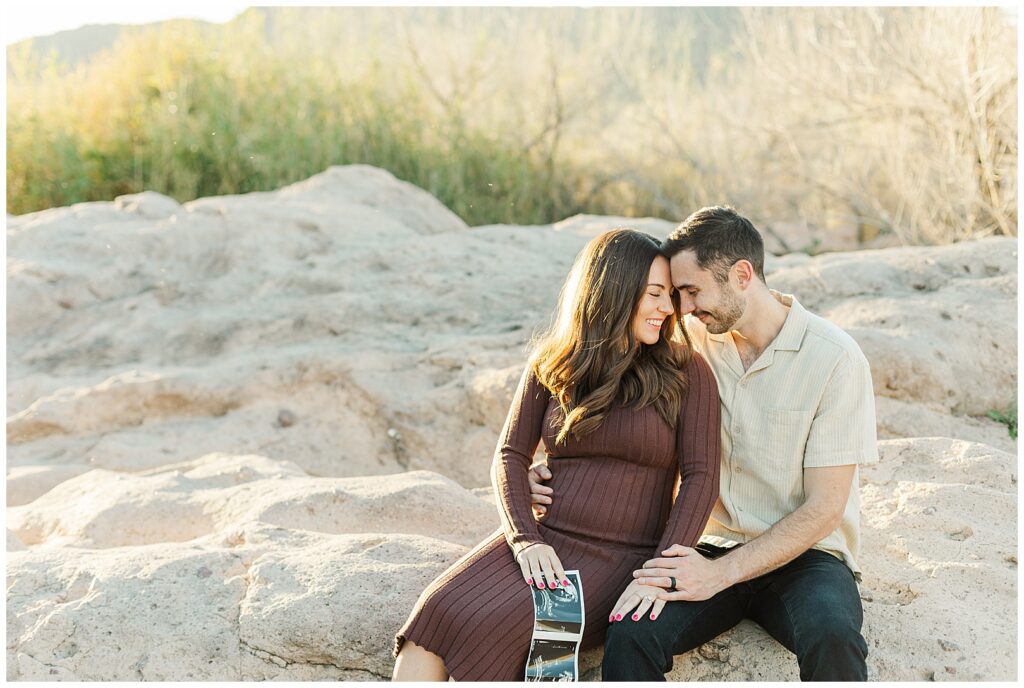 Phon D. Sutton Baby Announcement Photos | Couple with ultra sound sitting on rocks with beautiful mountain range in the back