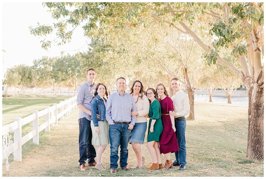 Family Photos at Morrison Ranch under big green trees near a lake and a white picket fence