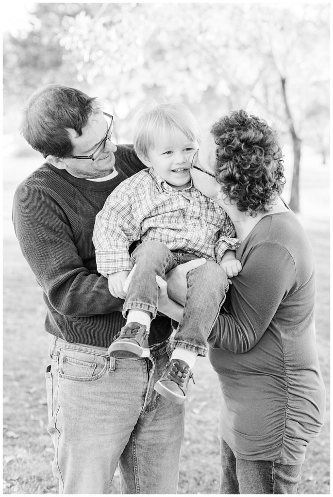 black and whit photo of mom and dad holding little boy and giving kisses at Morrison Ranch