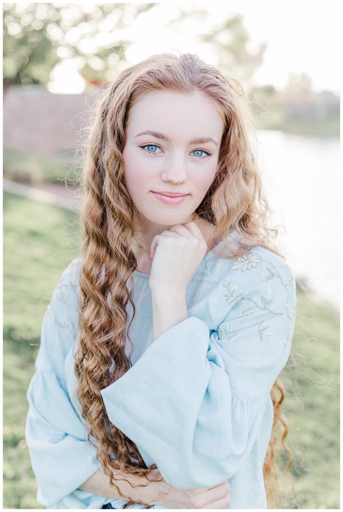 Addi's senior photos, girl wearing a blue shirt smiling directly at camera with bright blue eyes
