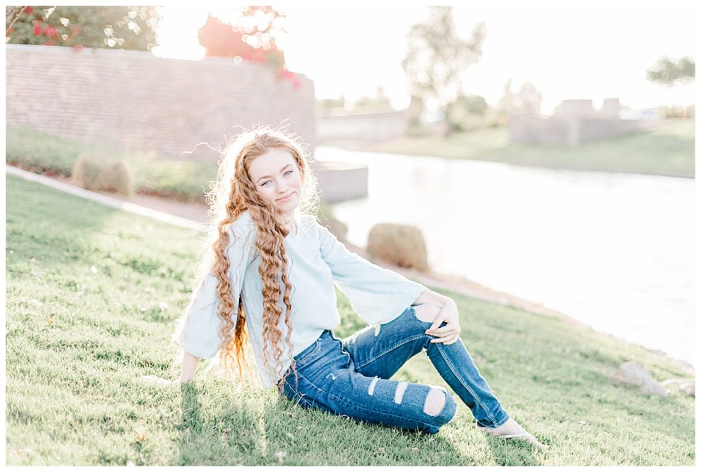 Girl sitting on grass at Layton Lakes smiling toward camera