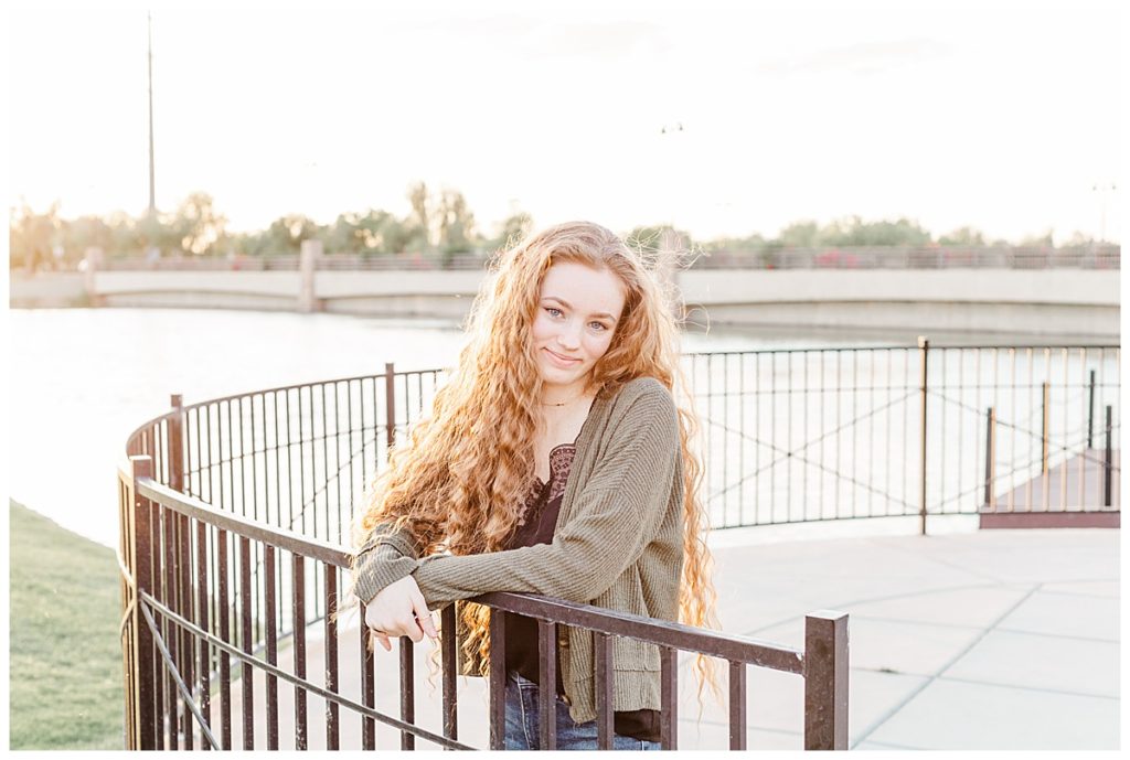 Girl standing in front of Layton Lakes, leaning on railing