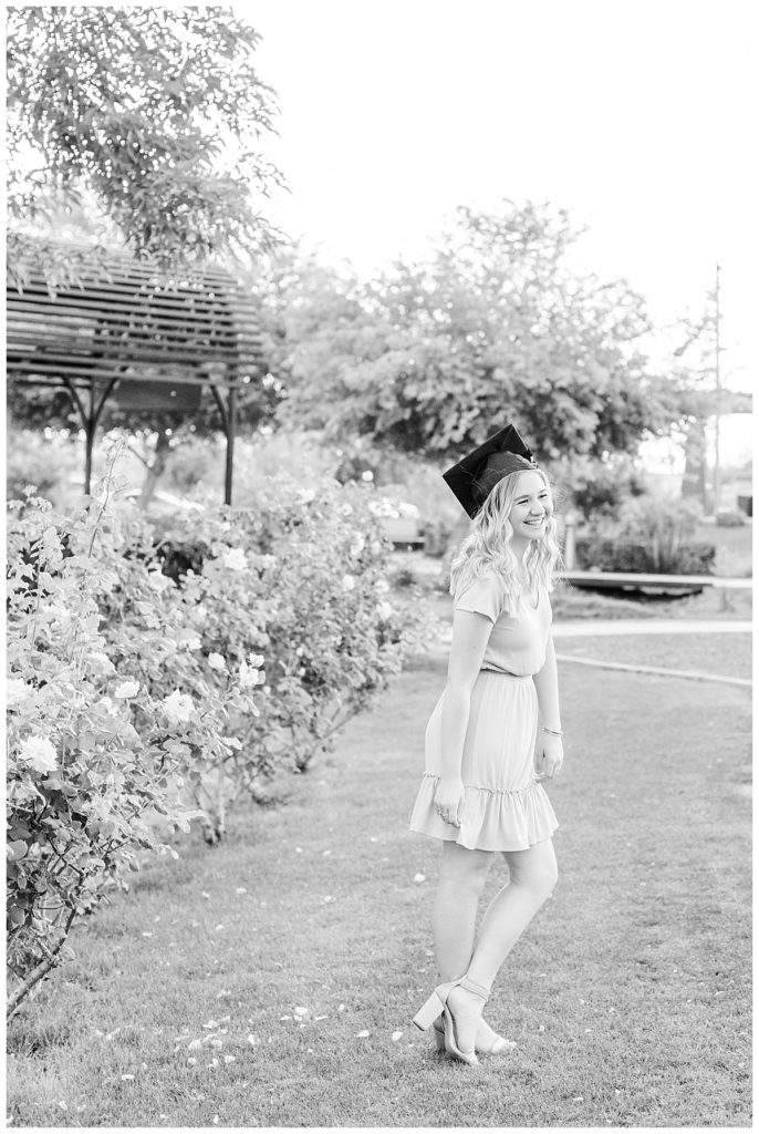 girl wearing cap and a little dress standing in the MCC Rose Garden laughing