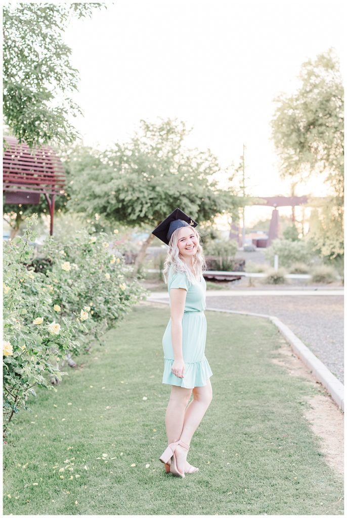 girl wearing graduation cap and a little blue dress, Senior photos at a rose garden