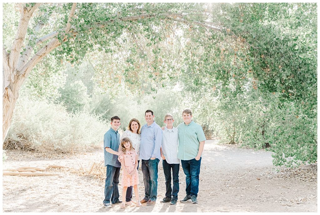 Ison's family photos at queen creek wash standing together under big bowing tree