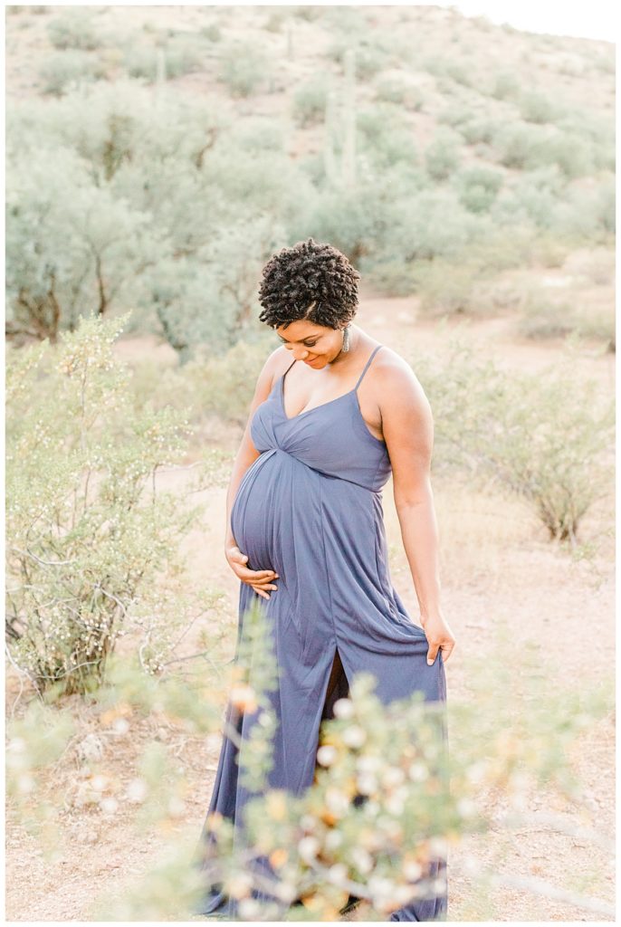 pregnant mom wearing a long purple dress smiling toward her baby
