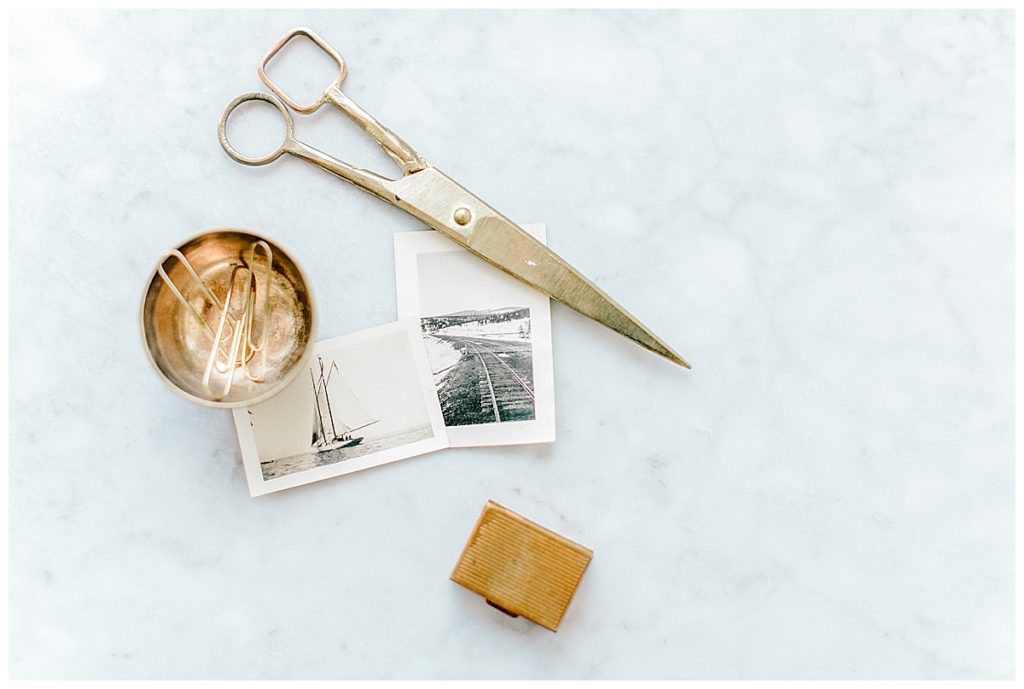 travel photos next to gold scissors and gold paperclips