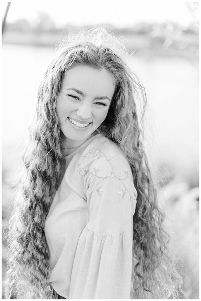 black and white photo of a senior girl laughing with her hair blowing in the wind | ‘Perfectly Candid' Photos
