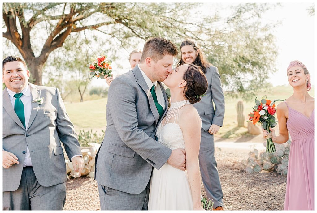 Bride and groom kissing and full bridal party clebrating at the Golf Club at Johnson Ranch Wedding