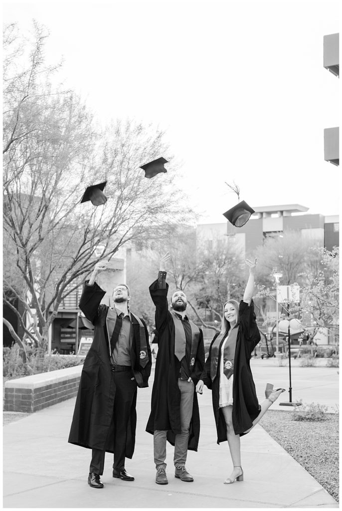 GCU Light & Airy senior graduation black and white photo, wearing cap and gown and tossing caps in air
